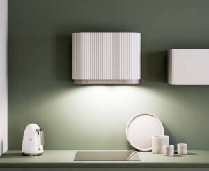 Biały okap kuchenny na zielonej ścianie kuchni.