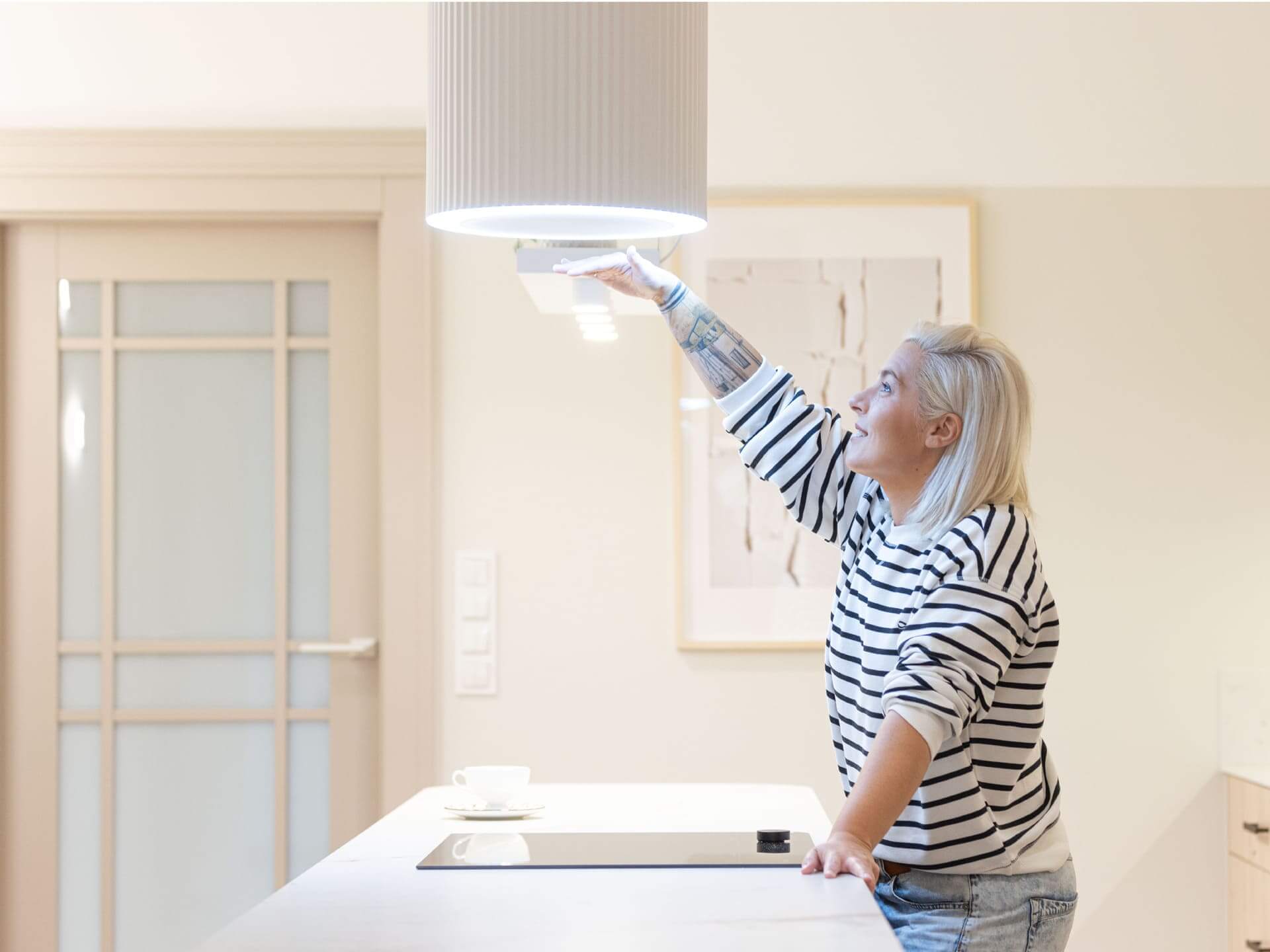 Kobieta dotykająca nowoczesnego okapu kuchennego.